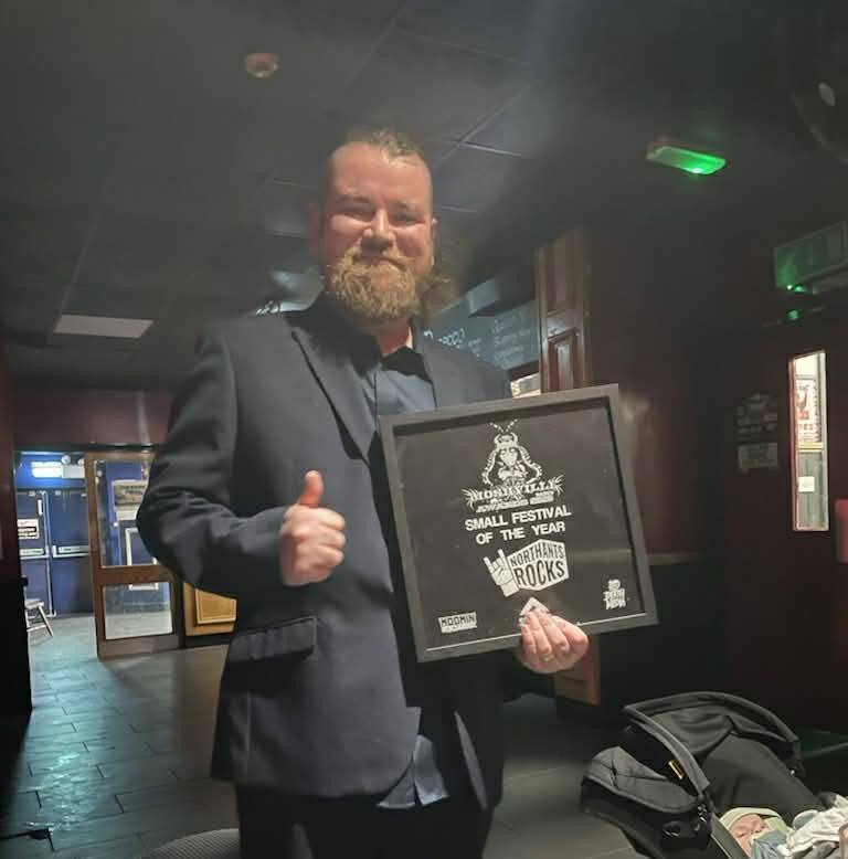 Photo of a silhouette of 2 dancers posing in front of a red curtain.